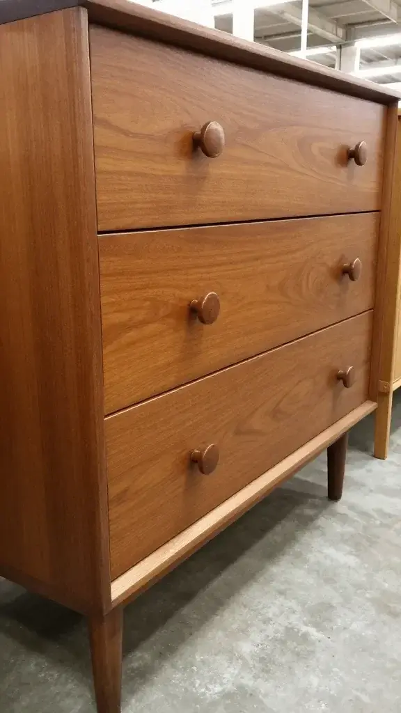 Hand shaking mid-century dresser, visible wobble, thrift store aisle
