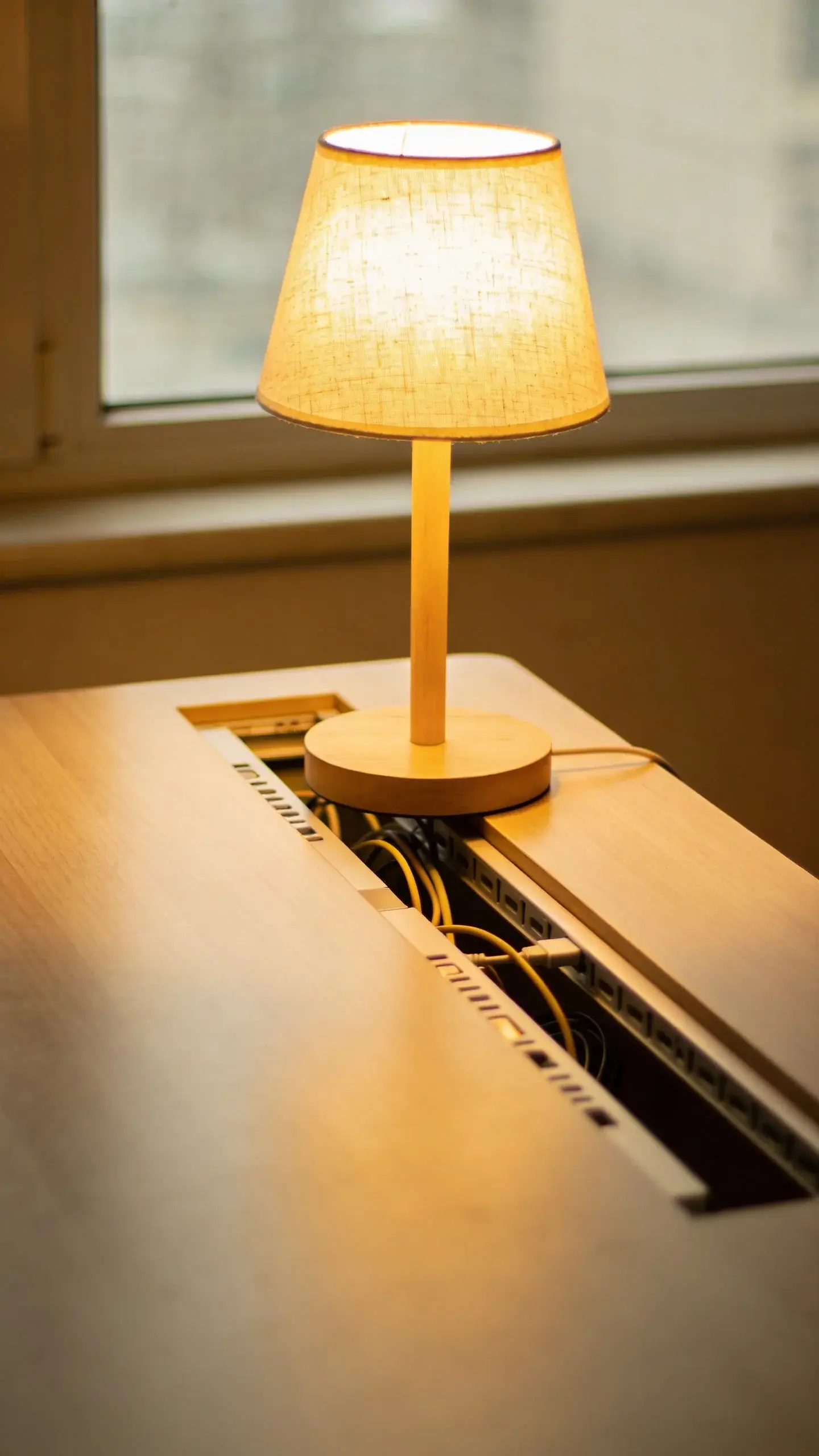 compact desk by window with warm lamp, hidden cables