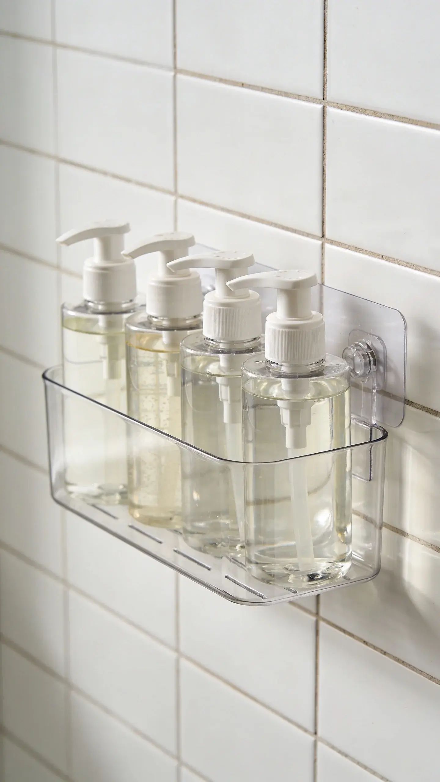 Adhesive shower caddy on tiled wall with shampoo bottles