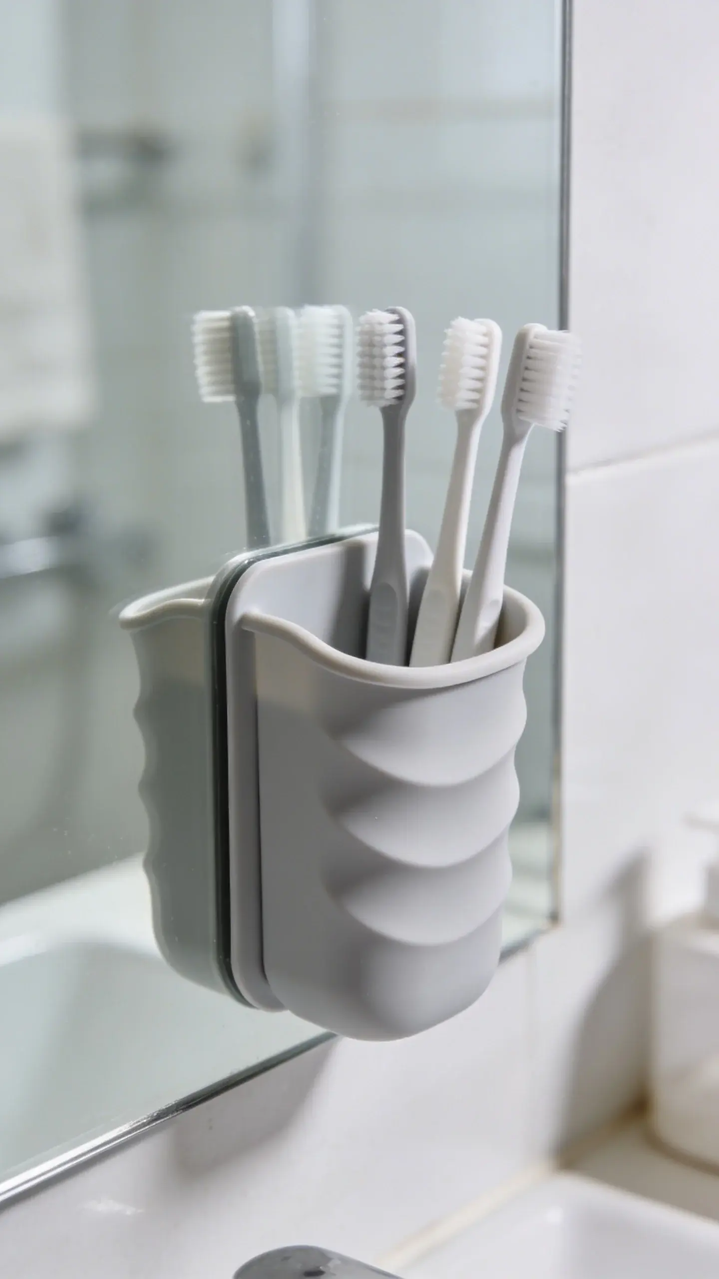 Silicone toothbrush holder mounted on bathroom mirror