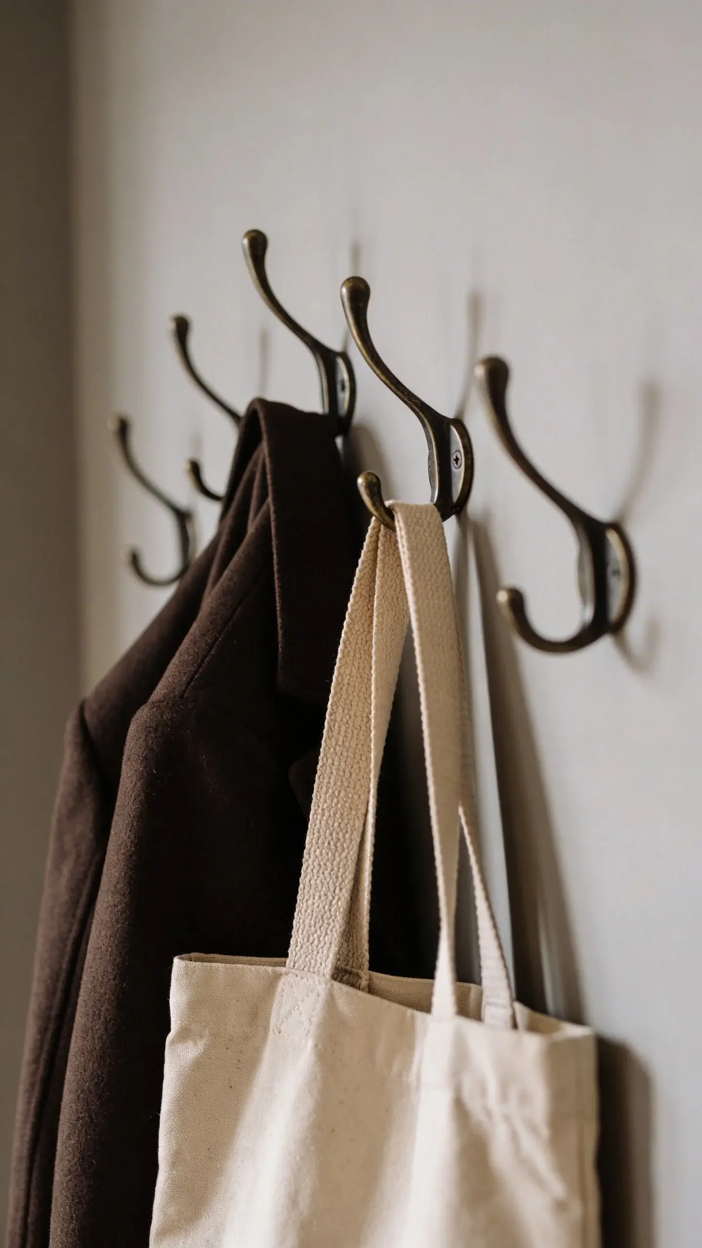 Staggered wall hooks holding coat and canvas tote